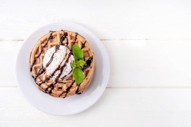 Dondurma ve çikolata soslu bir yığın çikolatalı waffle. Dondurmalı waffle, çikolata soslu çiseleme ve nane şekeri.