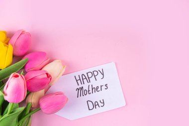 Anneler gününde lale çiçeği buketi, pembe kurdeleli hediye kutusu ve mutlu anneler günü etiketi. Tebrik kartı arkaplanı, poster, broşür, broşür, tanıtım malzemeleri, web sitesi