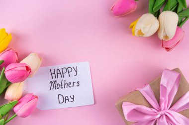 Anneler gününde lale çiçeği buketi, pembe kurdeleli hediye kutusu ve mutlu anneler günü etiketi. Tebrik kartı arkaplanı, poster, broşür, broşür, tanıtım malzemeleri, web sitesi