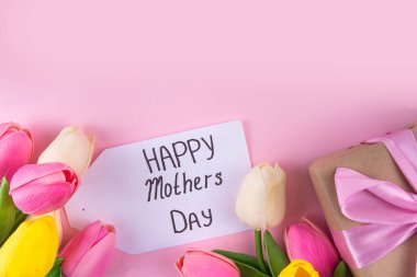 Anneler gününde lale çiçeği buketi, pembe kurdeleli hediye kutusu ve mutlu anneler günü etiketi. Tebrik kartı arkaplanı, poster, broşür, broşür, tanıtım malzemeleri, web sitesi