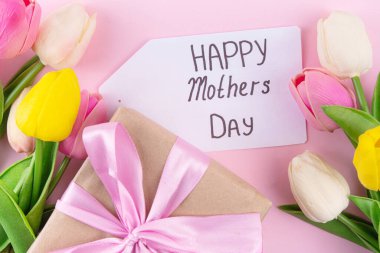 Anneler gününde lale çiçeği buketi, pembe kurdeleli hediye kutusu ve mutlu anneler günü etiketi. Tebrik kartı arkaplanı, poster, broşür, broşür, tanıtım malzemeleri, web sitesi