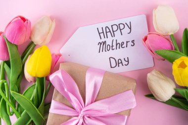 Anneler gününde lale çiçeği buketi, pembe kurdeleli hediye kutusu ve mutlu anneler günü etiketi. Tebrik kartı arkaplanı, poster, broşür, broşür, tanıtım malzemeleri, web sitesi