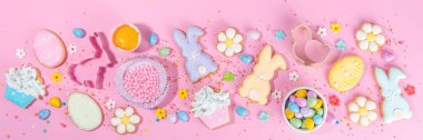 Cute pink sweet baking flat lay for Easter holiday. Cooking background with baking ingredients, rolling pin, whisk for whipping, cookie and cutters, sugar sprinkling, flour, top view copy space 