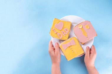 Babalar günü tatili fikri, hoş bir sürpriz hediye. Babaya kahvaltı hazırlayan çocuk, yaratıcı bir şekilde dekore edilmiş tost sandviçleri kravat, papyon, yazıt babamı seviyorum. Üst görünüm kopyalama alanı, mavi arkaplan