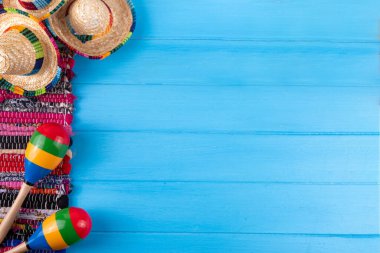 Meksika bayramı arkaplanı, serape çizgili battaniye veya panço şapkası, eski mavi ahşap arka planda marakas. Meksika Cinco de Mayo festivali, Meksika Bağımsızlık Günü geçmişi