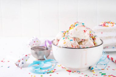 Doğum günü pastası dondurması. Doğum günü pastasının kase porsiyonu renkli şekerli vanilyalı dondurma, masada doğum günü süslemeleri olan funfetti, fotokopi masası.