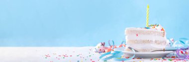 Doğum günü pastası dilimi, parti dekore masasında. Doğum günü pastası beyaz kremalı, şeker serpintili funfetti ve mum, kopyalama alanı