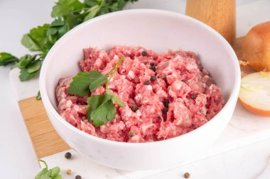 Yemek pişirme geçmişi. Çiğ taze kıyma, biftek, kuzu eti, beyaz mermer bir masada otlar, baharatlar ve soğanlar.
