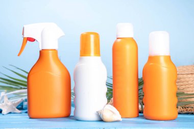 Güneş kremi maketi, plaj çantası, bayan şapkası, parmak arası terlikler ve renkli parlak arka planda tropik yapraklar. Güneş koruması, güneş kremi şişesi, yaz tatili konsepti. 