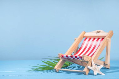 Hasır şapkalı yaz tatili arka planı, parmak arası terlikler, yaz aksesuarları, şezlonglu dekor ve tropikal yapraklar.