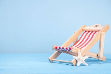 Hasır şapkalı yaz tatili arka planı, parmak arası terlikler, yaz aksesuarları, şezlonglu dekor ve tropikal yapraklar.