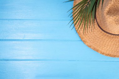 Hasır şapkalı yaz tatili arka planı, parmak arası terlikler, yaz aksesuarları, şezlonglu dekor ve tropikal yapraklar.