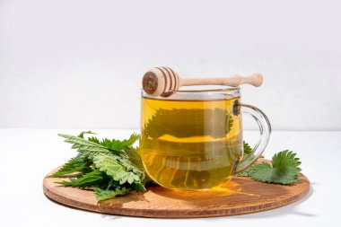 Nettle Tea sıcak bitkisi şeffaf cam bardakta içecek. Organik doğal bitkisel çay kafeinsiz, organik çiğ ısırgan otu yapraklarıyla yapılır. Alternatif bitkisel ilaç. Isırgan otu, urtica.