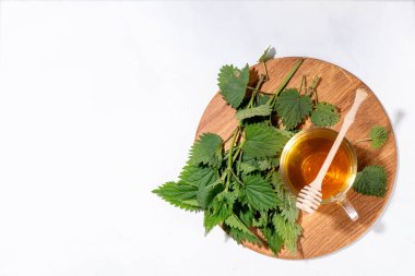 Nettle Tea sıcak bitkisi şeffaf cam bardakta içecek. Organik doğal bitkisel çay kafeinsiz, organik çiğ ısırgan otu yapraklarıyla yapılır. Alternatif bitkisel ilaç. Isırgan otu, urtica.