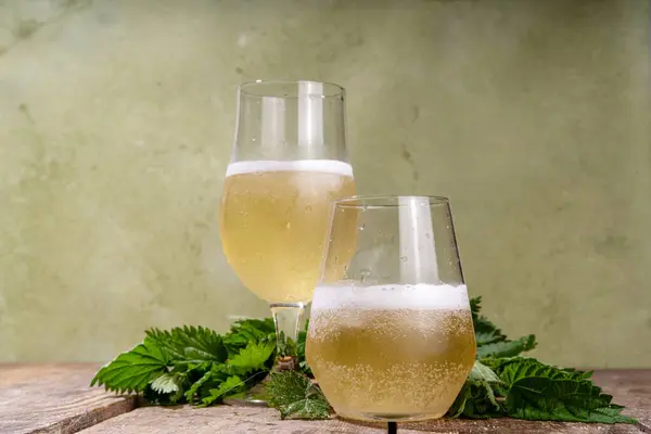 Nettle craft fizz beer alcohol alternative drink, soft organic refreshing nettle bubbly beverage, hard plant cider  with fresh nettle leaves copy space