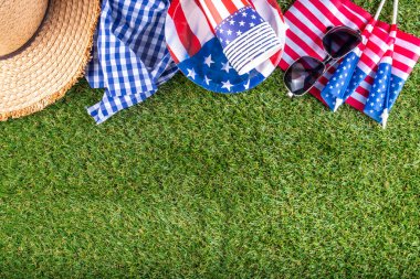 4 Temmuz, Bağımsızlık Günü geleneksel Amerikan piknik geçmişi. Tabaklar, bardaklar, yeşil çimenlik ya da çayır çimenliğindeki Amerikan bayrakları, piknik için battaniye ya da masa örtüsü, güneş gözlüğü, fotokopi alanı üst görünümü