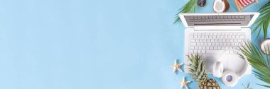 İş ve tatil. Yaratıcı yaz ofis dairesi beyaz dizüstü bilgisayarı, tropikal yaz aksesuarları, palmiye yaprakları, güneş gözlükleri, parmak arası terlikler, ananas ve açık mavi arka planda hindistan cevizi ile yatıyordu.