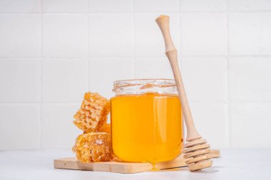 Bal kaşığı ve bal peteğiyle küçük bir kavanozda altın çiçek balı 