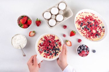Fırında yoğurt pişirmek sağlıklı bir tatlı. Kadın el yapımı fırın Yunan yoğurt tatlısı taze donmuş böğürtlenlerle, beyaz mutfak masasında, malzemelerle, üst manzara