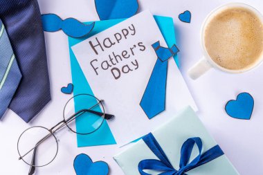 Aksesuar ve dekor, Babalar Günü tebrik kartı, babamın tatil yeri, zarf, kartpostal, bıyık, peçete, kravat, kahve ve mavi arka planda hediye kutusu.