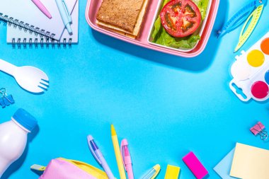Healthy school meal, back to school concept. Children packed lunch box with balanced diet snack food - yogurt, cereal toast sandwich, apple, fresh vegetable salad, high-colored bright background