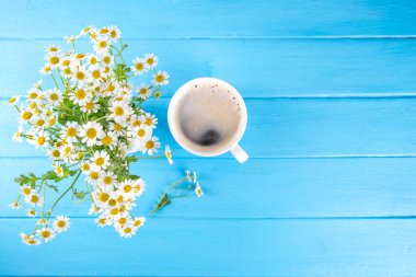 Papatya çiçeği buketi, kitap, çay ya da kahve fincanı, gevşeme tatili basit yaşam yaz arkaplanı, açık mavi ahşap arka plan, üst manzara fotokopi alanı. İyi günler, günaydın.