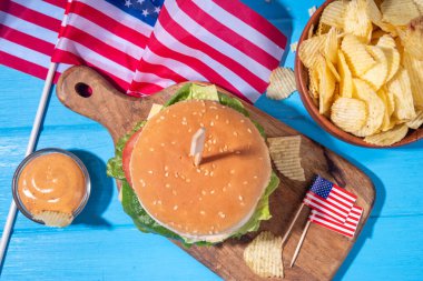 Lezzetli çizburger, patates kızartması ve soslu vatansever Amerikan bayrağı. 4 Temmuz, Bağımsızlık Günü piknik yemeği, ABD temalı bbq hamburger fotokopi alanı