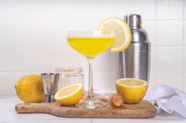 Tatlı ve ekşi alkol arısı dizleri kokteyli. Ev yapımı narenciye, bal arısı dizleri, malzemelerle birlikte beyaz arka planda sert ışık ve bar aletleriyle içerler.