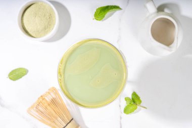 Kremalı matcha martini kokteyli Matchatini, modaya uygun soğuk yaz kokteyli. Alkolsüz kibrit mocktail ya da alkol kokteyli, martini bardaklarında yeşil kibrit tozu, arka planda sert ışık