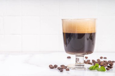 Sert espresso kahveli, tatlı likörlü, kremalı, kremalı, kremalı, fıstıklı kremalı, beyaz arka planda, sert ışıklı ve bar aletli.