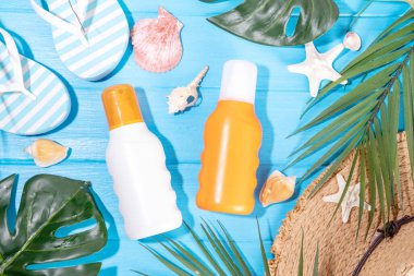 Güneş kremi maketi, plaj çantası, bayan şapkası, parmak arası terlikler ve renkli parlak arka planda tropik yapraklar. Güneş koruması, güneş kremi şişesi, yaz tatili konsepti. 