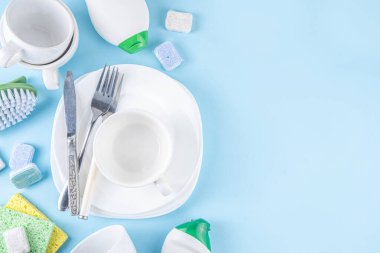 Bulaşık tableti, deterjan ve aksesuarlar için tabak, bardak ve çatal bıçak takımı açık mavi arka plan fotokopi alanı 