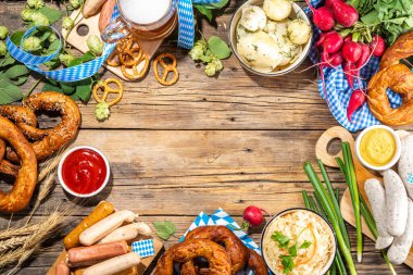 Oktoberfest holiday greeting card, menu, invitation background, Traditional Oktoberfest festival food, bavarian sausages, pretzels, potato, sauerkraut, beer mug on wooden background, copy space above