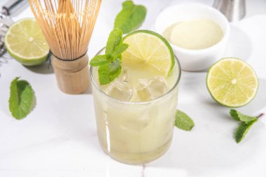 Limon ve kireç sağlıklı ekşi margarita kokteyli, narenciye ve taze naneli buzlu kibrit yeşil çay, beyaz arka planda sert ışık ve bar kapları.