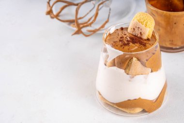 Moda dalgona tiramisu tatlısı. İki bardak kremalı kremalı kahve tiramisu, üzerine de hazır kahve köpüğü ve savoyardi.