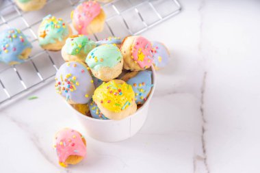 Tatlı renkli donutlar tatlı delikleri, küçük çörekler renkli jöle ve şeker parçacıkları, beyaz mutfak masasında 