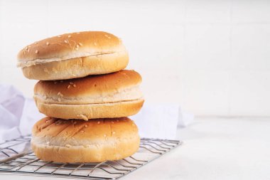 Ev yapımı taze pişmiş hamburger çörekleri. Geleneksel Amerikan susamlı çörekleri beyaz mutfak masasında.