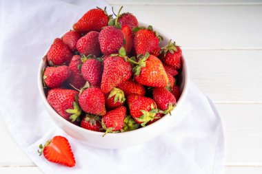 Beyaz ahşap masa fotokopi alanındaki bir kasede taze kırmızı çilek.