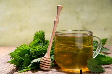 Nettle Tea sıcak bitkisi şeffaf cam bardakta içecek. Organik doğal bitkisel çay kafeinsiz, organik çiğ ısırgan otu yapraklarıyla yapılır. Alternatif bitkisel ilaç. Isırgan otu, urtica.