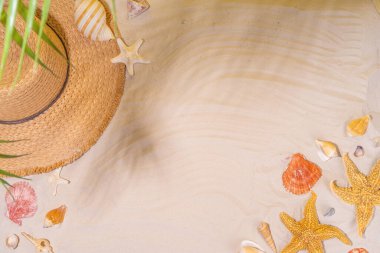 Yaz güneşli kum düzlüklerinde hasır şapkalar, terlikler ve deniz kabukları ile deniz kumu arka planında fotokopi uzayı uzanıyordu.