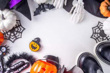 Çocukların Cadılar Bayramı partisi için hazırlıklar, şeker mi şaka mı geleneği. Geleneksel çocuk Cadılar Bayramı kostümlü cadı, hayalet, iskelet, balkabağı aksesuarları, şeker kovası, beyaz arka planda dekor.