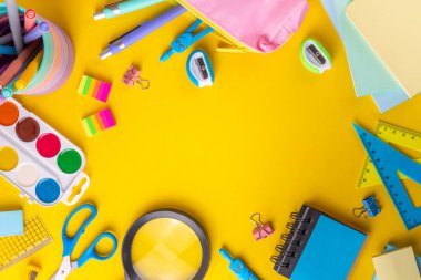 Okul ekipmanları parlak sarı düz yerde yatıyordu. Çeşitli okul ve ofis malzemeleri, aksesuarlar. Okul satışına geri dön. Üst görünüm kopyalama alanı