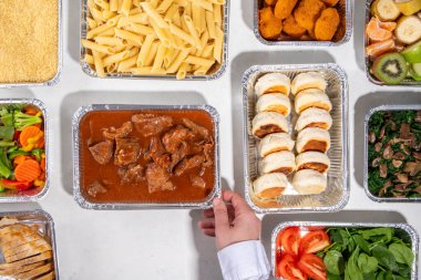 Yemek pişirme konsepti. Çeşitli çeşit mezeler: tahıl gevreği, makarna, makarna, pişmiş ve taze sebzeler, et, tavuk, nugget, kahvaltı krepleri ve yiyecek kabında meyve. 