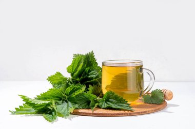 Nettle Tea sıcak bitkisi şeffaf cam bardakta içecek. Organik doğal bitkisel çay kafeinsiz, organik çiğ ısırgan otu yapraklarıyla yapılır. Alternatif bitkisel ilaç. Isırgan otu, urtica.