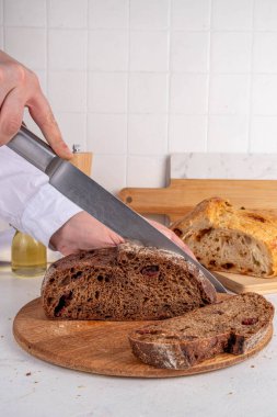 Ev yapımı taze ekşi ekmek. Beyaz bir masada ev yapımı çavdar ekmeği ve beyaz ekmek. Resimdeki kızlar taze kokulu ekmek fotokopi odasını kesiyorlar.