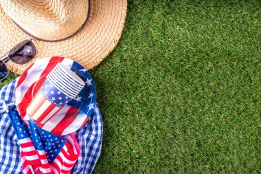 4 Temmuz, Bağımsızlık Günü geleneksel Amerikan piknik geçmişi. Tabaklar, bardaklar, yeşil çimenlik ya da çayır çimenliğindeki Amerikan bayrakları, piknik için battaniye ya da masa örtüsü, güneş gözlüğü, fotokopi alanı üst görünümü