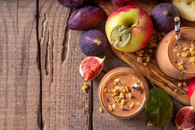 Sonbahar meyveli yoğurt içeceği. Taze meyve, erik, incir, elma, yulaf ve fındık, ahşap arka plan fotokopi alanı ile iki bardak çırpılmış meyve suyu.