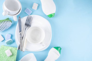 Bulaşık tableti, deterjan ve aksesuarlar için tabak, bardak ve çatal bıçak takımı açık mavi arka plan fotokopi alanı 