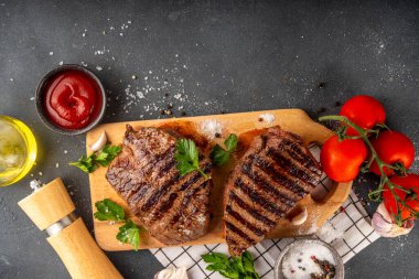 Ahşap kesme tahtasında ızgara biftek, ketçap sosu ve baharat, üst görünüm kopya alanı.