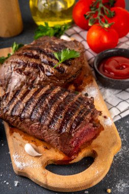 Ahşap kesme tahtasında ızgara biftek, ketçap sosu ve baharat, üst görünüm kopya alanı.